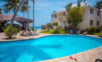 a resort with a large pool surrounded by lounge chairs and palm trees , overlooking the ocean at Beachcomber at Las Canas