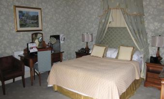 a large bed with a canopy is in the middle of a room with gray walls and a desk at Woodlands Hotel