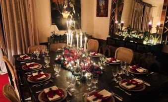a beautifully set dining table with red plates , glasses , and candles in a room decorated for christmas at The Good House