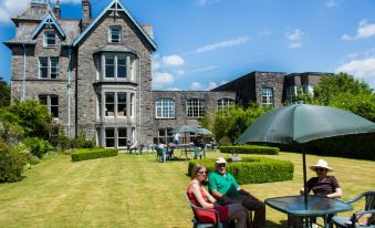 a man and a woman are sitting at a table in front of a house , enjoying their time outdoors at Cumbria Grand Hotel