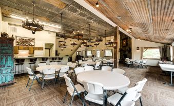 a large , open room with white tables and chairs , wooden ceiling beams , and pendant lights at North Texas Jellystone Park