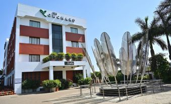 a modern building with a large metal sculpture in front of it , surrounded by palm trees and other greenery at The Orchard