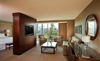 a living room with a couch , chairs , and a tv . also a dining table in the room at Sheraton Valley Forge King of Prussia
