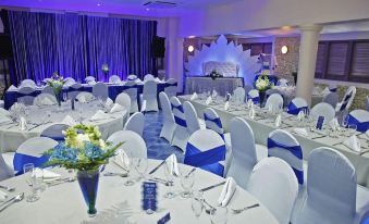 a large banquet hall set up for a formal event , with tables covered in white tablecloths and chairs arranged around them at Infinity on the Beach