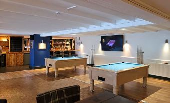 a pool table and a bar are set up in a room with wooden floors at The Fairy Falls Hotel