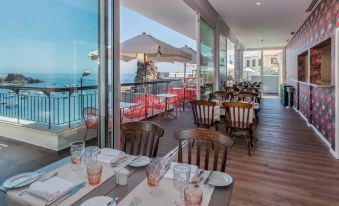 an outdoor dining area with wooden tables and chairs , all set for a meal , overlooking the ocean at Pestana Churchill Bay