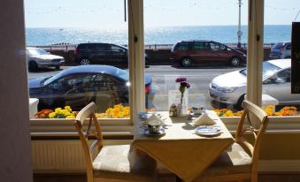 a table with a vase of flowers and other items is set up in front of a window overlooking the ocean at Atlanta
