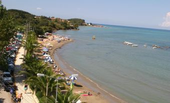 a beautiful beach with clear blue water , white sand , and numerous people enjoying the sunny day at Pegasus Hotel