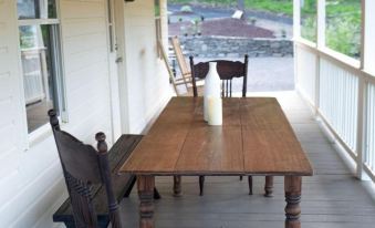 a wooden dining table and chairs on a porch with string lights overhead , creating a cozy atmosphere at Stonehill's Farmhouse