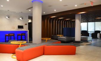 a modern lounge area with red and blue seating , wooden columns , and a blue accent wall at Best Western Plus Aston Hall Hotel