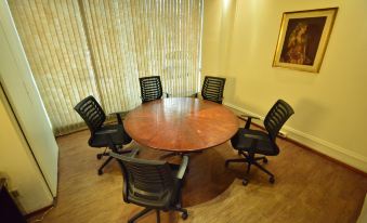 a conference room with a wooden table surrounded by six black chairs , and a painting on the wall at Oxford Hotel