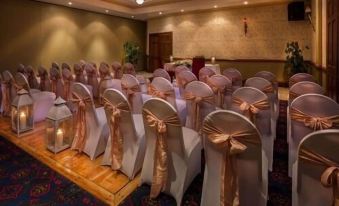 a well - decorated room with white chairs and pink sashes , ready for an event or meeting at Breffni Arms Hotel