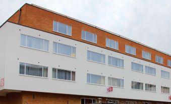 a modern apartment building with orange and white exterior , large windows , and a red sticker on the side at Best Western Plus London Croydon Aparthotel