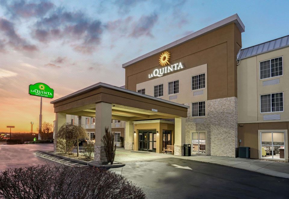 an exterior view of a la quinta inn hotel , with the sun setting in the background at La Quinta Inn & Suites by Wyndham Knoxville North I-75