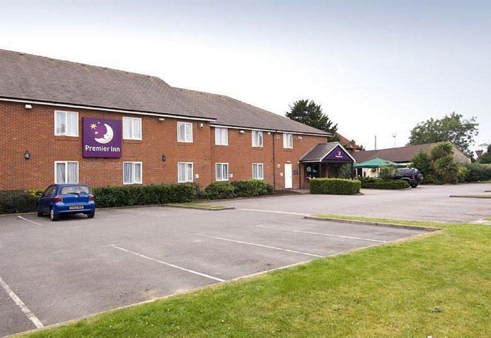"a brick building with a purple sign that says "" premier inn "" on the front , and a parking lot in front" at Swindon North