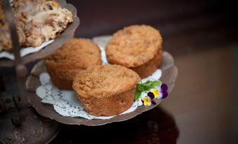 a stack of muffins on a plate with a flower and a small cake in the background at Steeles Tavern Manor