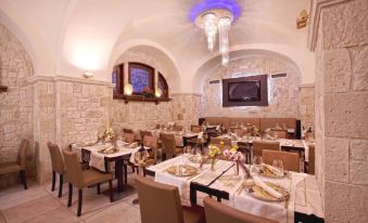 a restaurant with white tablecloths and chairs , gold flatware , and a large screen on the wall at Hotel Cenacolo