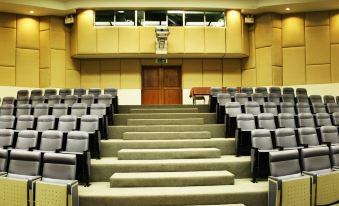 a large , empty auditorium with rows of gray carpeted seats and a wooden door at the end at DoiTung Lodge