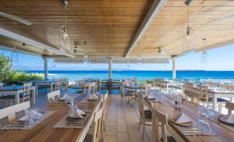 an outdoor dining area with wooden tables and chairs , surrounded by a view of the ocean at Saint George Hotel