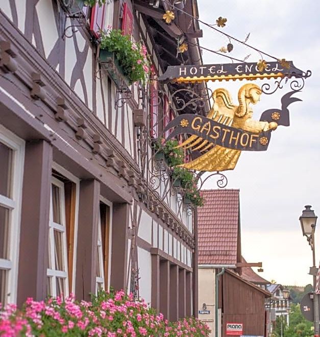 "a sign for "" hotel alte gasthof "" hangs above a street with flowers and buildings" at Hotel Restaurant der Engel, Sasbachwalden