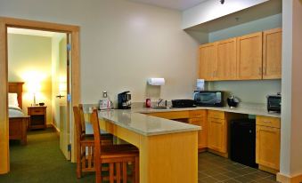 a kitchen with wooden cabinets , a counter , and chairs , as well as a sink and microwave at Nature Inn at Bald Eagle