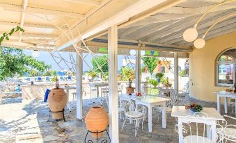 an outdoor dining area with white tables and chairs , as well as a pool in the background at Palladion