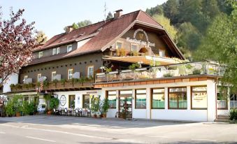 a large , two - story house with a balcony and wooden accents is surrounded by potted plants at Gasthof Zur Post