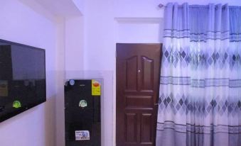 a small room with a television mounted on the wall , a refrigerator , and a door at Luxury Apartment