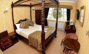 a luxurious bedroom with a four - poster bed , a tv , and a dining table in the room at Buckatree Hall Hotel