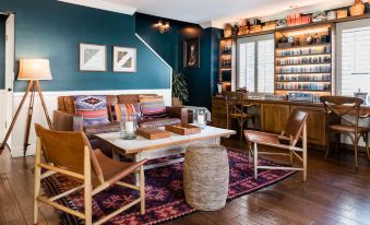 a cozy living room with a wooden coffee table , brown chairs , and a rug on the floor at Hotel Carmel