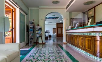 a spacious room with a green and white tile floor , a wooden desk , and a doorway leading to another room at Hotel Martino