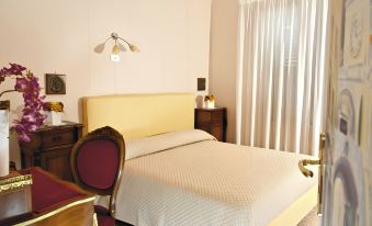 a neatly made bed with a beige headboard is situated in a room with white curtains at Leonardo's