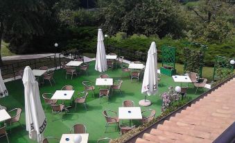 an outdoor dining area with several tables and chairs , some of which are covered in white tablecloths at Ca' Del Bosco