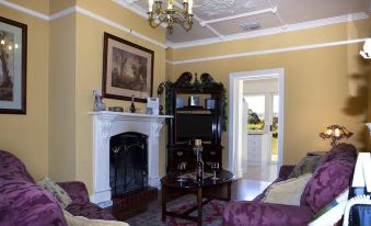 a living room with a fireplace , two couches , and a dining table in the background at Barossa Shiraz Estate