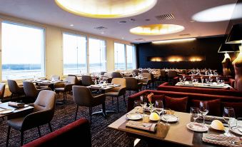 a large dining room with multiple tables and chairs arranged for a group of people to enjoy a meal together at Clarion Hotel Arlanda Airport Terminal