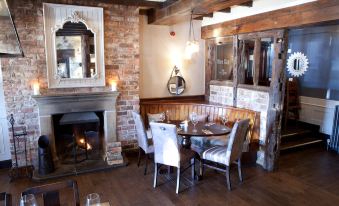 a cozy restaurant with wooden floors , brick walls , and a dining table surrounded by chairs at Premier Inn Northwich (Sandiway)