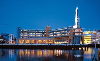 a large , modern building with multiple floors and balconies lit up at night , situated near a body of water at Scandic Ishavshotel