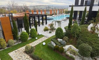 a modern building with a pool and lush greenery , viewed from an elevated perspective on a grassy area at Hotel Mirror Skopje