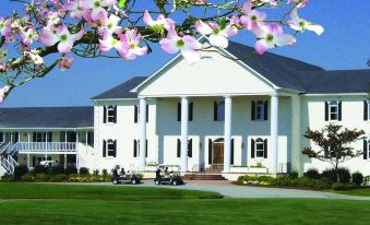 a large white building with a porch and several golf carts parked in front of it at Beau Rivage Golf and Resort