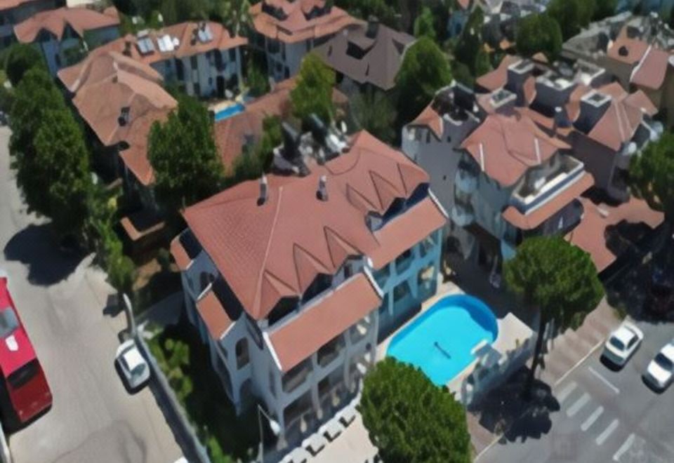 aerial view of a residential area with multiple buildings and a swimming pool surrounded by trees at Arya Otel