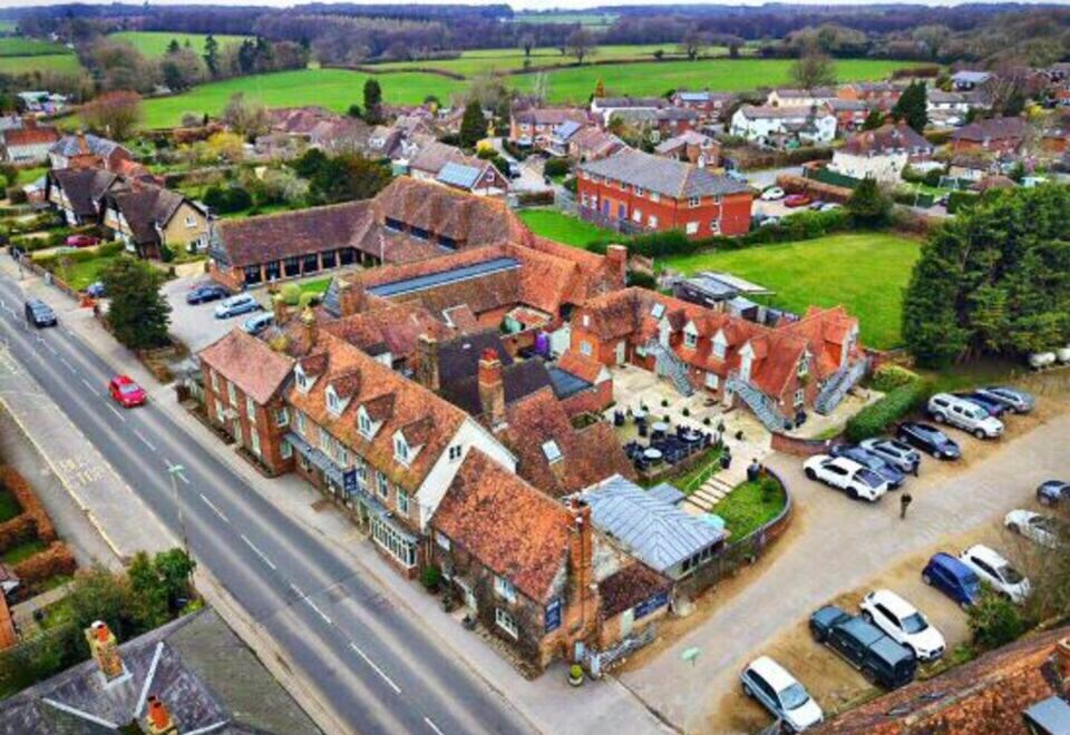 aerial view of a small village with red - roofed buildings and green fields , surrounded by other buildings and cars on the road at The White Hart