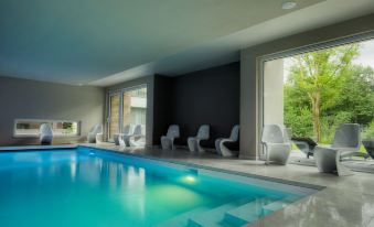 a modern indoor pool with a large window and white lounge chairs surrounding it , creating a relaxing atmosphere at Utopia Hotel - Art & Nature Hotel