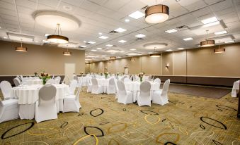 a large , empty banquet hall with white tables and chairs is set up for an event at Holiday Inn Morgantown - Reading Area