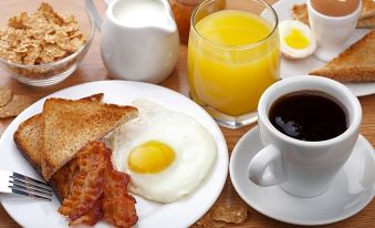 a table is set with a variety of breakfast foods including toast , eggs , bacon , toast , and orange juice at Boutique Hotel Ilio