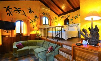 a cozy bedroom with a bed , a couch , and a staircase leading to a loft area at Hotel la Mansion Inn Arenal