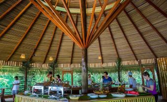 a group of people gathered around a dining table in a room with a thatched roof , enjoying a meal at Juma Amazon Lodge