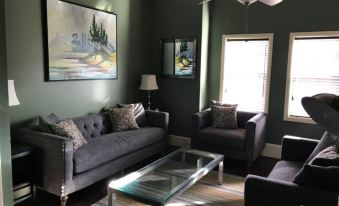 a living room with two gray couches , a glass coffee table , and a painting on the wall at Lofts on Main