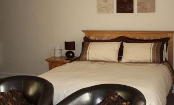 a bed with a wooden headboard and white sheets is shown in a bedroom with two lamps on either side at The Brewers Arms