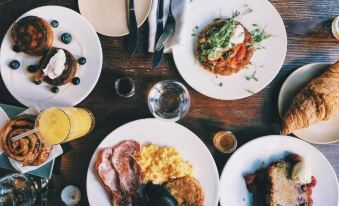 a wooden table is filled with various plates of food , including sandwiches and pastries , accompanied by glasses of wine at Silver Springs Hotel Uganda