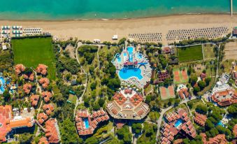 aerial view of a resort surrounded by green grass , trees , and a body of water at Aquaworld Belek